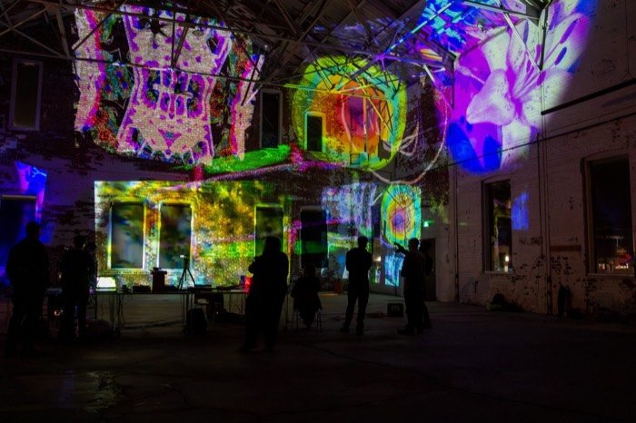 Colourful floral and abstract collage projections filling the warehouse walls at an OPTICKS Open Lab